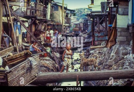 Philippines, Manila; Little boy over an open sewer of the slum he lives in. Stock Photo