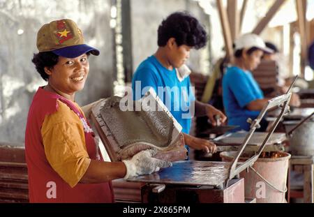 Philippines, Davao Women produce clay roof tiles with a mold at the Mindanao Land Foundation's tile factory. Stock Photo