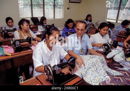 Philippines, Manila, manager instructs woman in a small-scale sewing workshop. Stock Photo