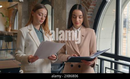 Business team colleagues Caucasian co-workers manager executives women businesswomen girls female managers in office together discuss papers contract Stock Photo