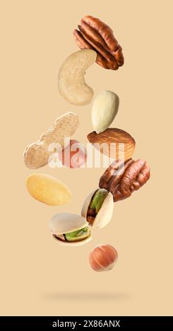 Many different nuts in air on beige background Stock Photo