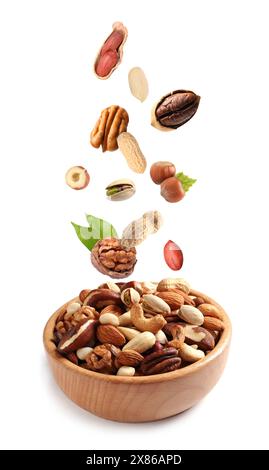 Different nuts falling into bowl on white background Stock Photo