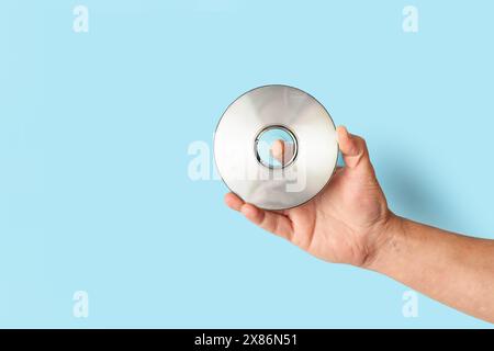 Man hand holding a compact disc on a blue background with copy space Stock Photo