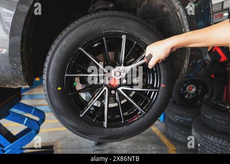 Car service, repair and maintenance concept - auto mechanic man changing tire in auto repair shop. Stock Photo