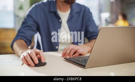 Project Manager Sitting at a Desk, Working on a Laptop Computer in an Office. Creative Marketing Specialist Planning a Project, Focus On Computer and Mouse. Typing Hands Stock Photo