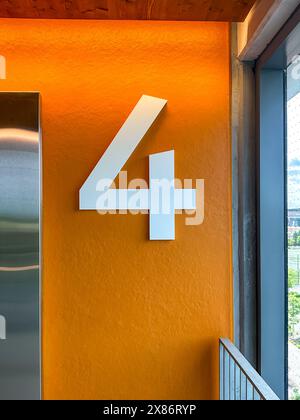 Floor level 4 in a parking ramp, garage, car parking with a large white number on an orange background. Stock Photo