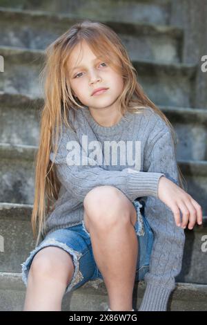 sad little girl sitting on stairs Stock Photo
