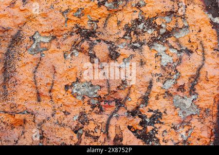 Texture of crumbling plaster wall painted with orange paint and sprayed with spots of brown paint. Stock Photo