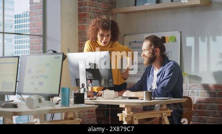 Two Creative Multicultural Colleagues Collaborate on a Project and Work Together as a Team. Marketing Manager and Designer Talking and Discussing Changes to an Advertising Campaign for a Startup. Stock Photo