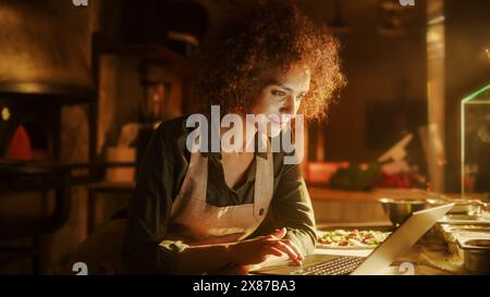 In Restaurant: Beautiful Female Chef Using Digital Tablet. Authentic Pizzeria With Delicious Organic Eco Food. Bi-racial Female Entrepreneur Working in Her Small Business Family Shop Stock Photo