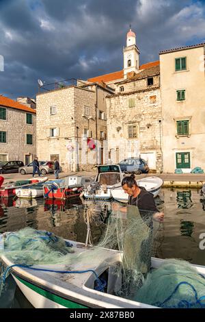 Fischer mit Netz auf seinem Boot im kleinen Hafen in der Altstadt von Sibenik, Kroatien, Europa Stock Photo