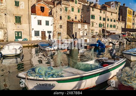 Fischer mit Netz auf seinem Boot im kleinen Hafen in der Altstadt von Sibenik, Kroatien, Europa Stock Photo