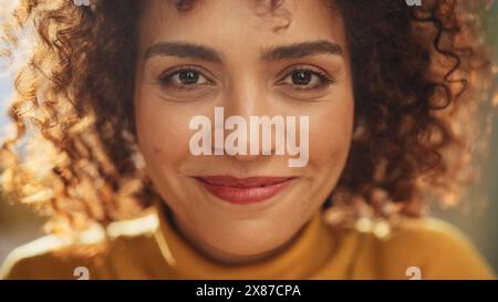 Close Up Portrait of a Young Middle Eastern Woman with Short Curly Hair, Looking for Camera, Wearing a Yellow Sweater. Beautiful Diverse Multiethnic Female Wearing Yellow Smiling and Being Happy. Stock Photo