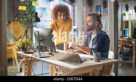 Portrait of Two Young Entrepreneurs Talking, Using a Computer to Discuss a Corporate Project. Stylish Managers Work on Financial and Marketing Projects in a Creative Agency. Stock Photo