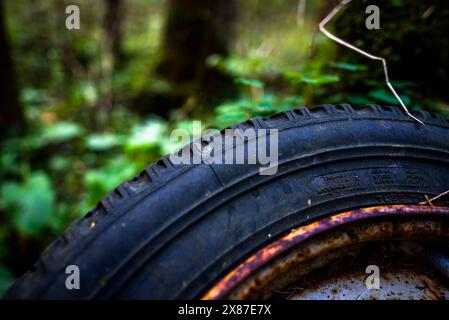 close-up of an old car wheel with a ruined black tire and rusty rim with peeling paint Stock Photo