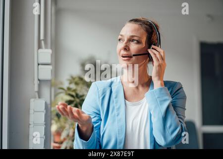 Confident mature businesswoman talking through headset in office Stock Photo