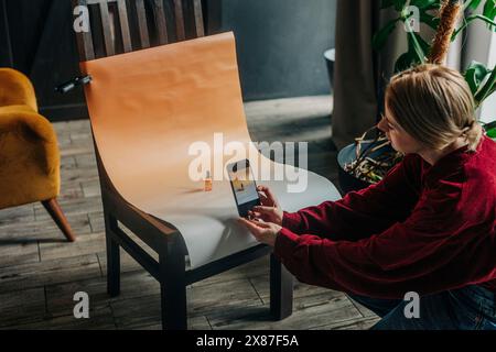 Businesswoman taking photo of cosmetic bottle through smart phone at home Stock Photo