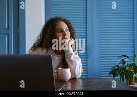 Thoughtful freelancer taking coffee break from work on laptop at home Stock Photo