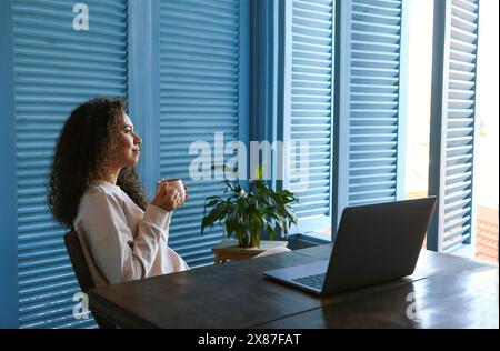 Freelancer taking coffee break from work on laptop at home Stock Photo
