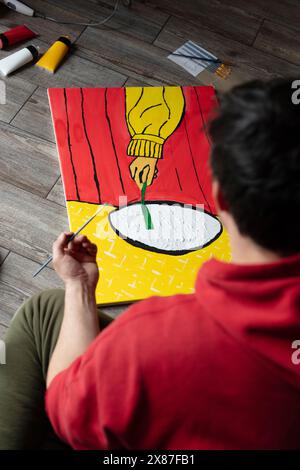 Painter holding brush near painting on floor at home Stock Photo