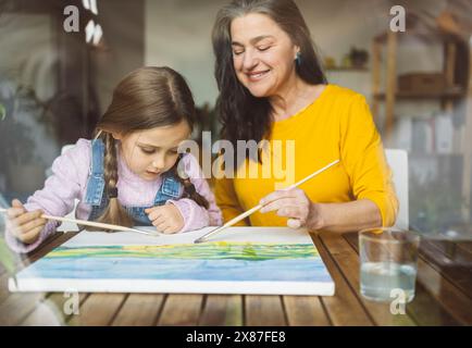 Grandmother and granddaughter painting together at table Stock Photo