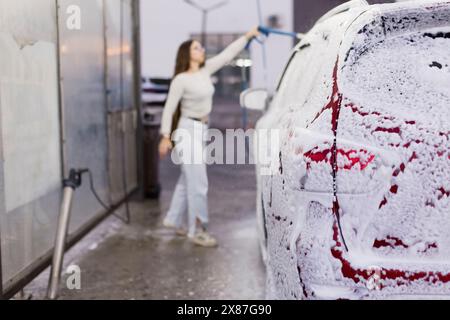 Woman using high pressure water and cleaning car at garage Stock Photo