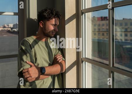 Smiling young man looking through window Stock Photo