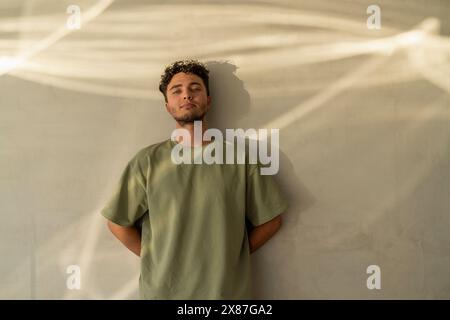 Smiling young man leaning on wall Stock Photo