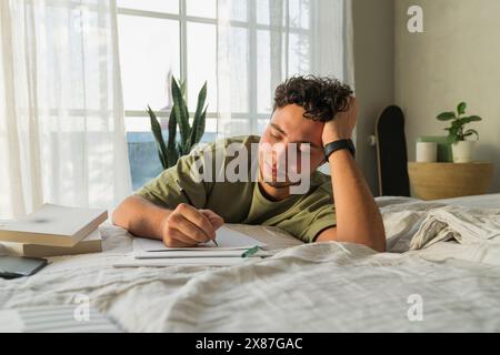 Young man leaning on bed and studying at home Stock Photo