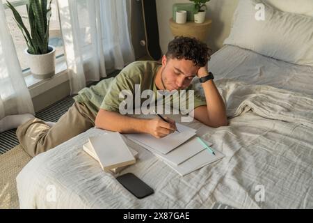 Man leaning and studying on bed at home Stock Photo