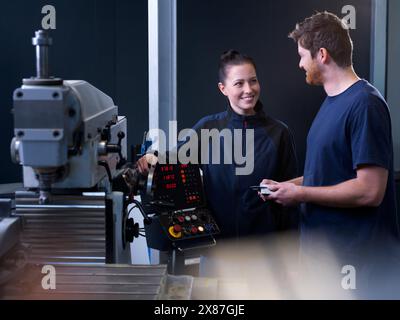 Engineers working on CNC machine at factory Stock Photo