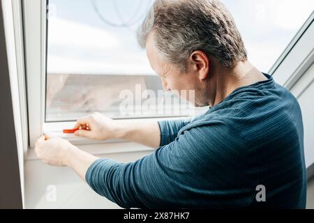 Man installing blinds on window at home Stock Photo