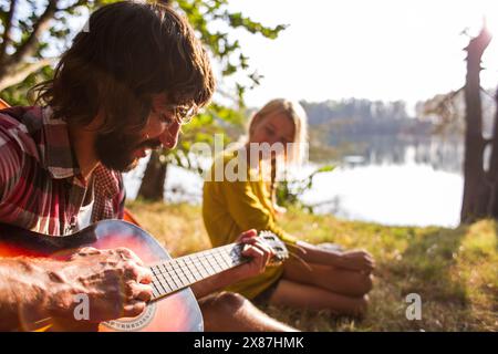 Smiling man playing guitar near girlfriend Stock Photo