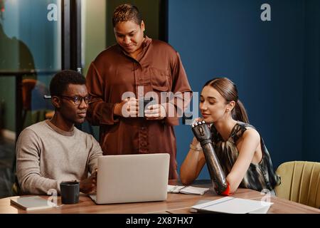 Diverse colleagues discussing over laptop at conference table in office Stock Photo