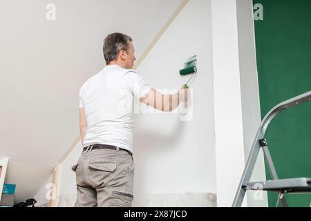 Man painting white wall using roller at home Stock Photo