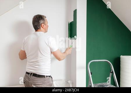 Man painting wall using roller at home Stock Photo