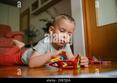 Boy lying on floor and playing with building toys at home Stock Photo