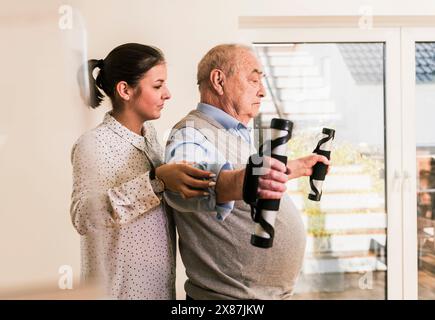 Doctor helping senior man exercising at nursing home Stock Photo