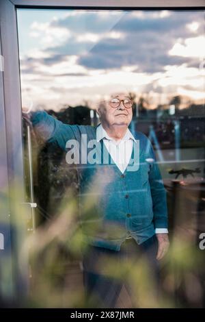 Thoughtful senior man looking out through window Stock Photo