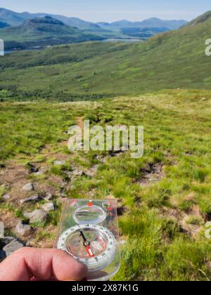 UK, Scotland, Hand of male hiker using navigational compass in Cairngorm Mountains Stock Photo