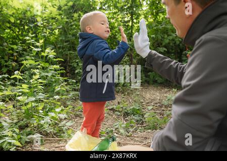 Son and father giving high-five at park Stock Photo