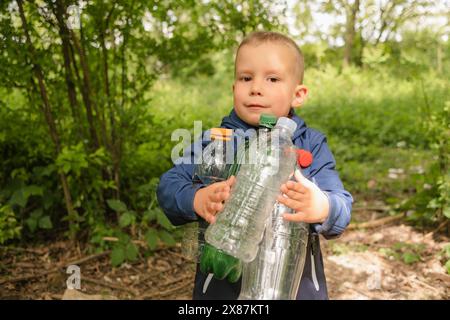 Cute boy holding plastic bottles at park Stock Photo