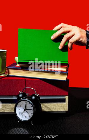 Hand of man opening green book on vintage record player by clock on table Stock Photo