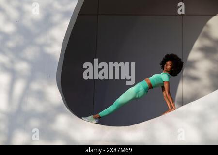 Confident woman with Afro hairstyle balancing on white wall Stock Photo