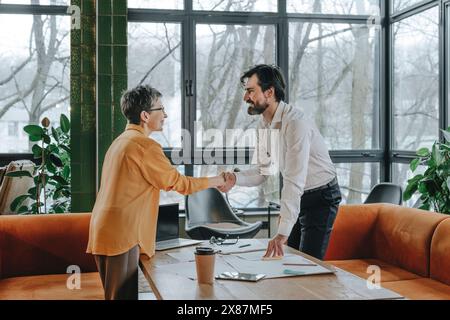 Smiling business people shaking hands in office Stock Photo