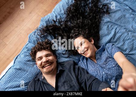 Happy couple lying down on bed at home Stock Photo