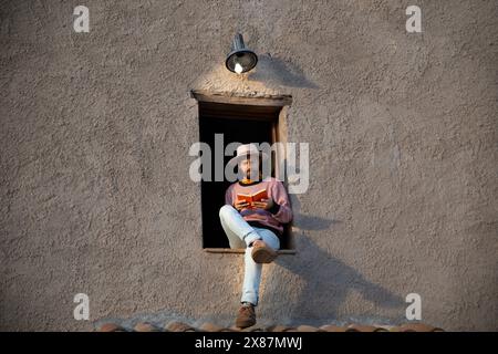 Man sitting on window and reading book Stock Photo
