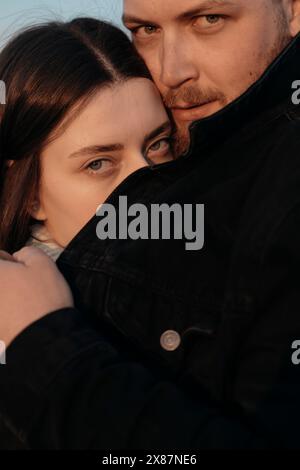 Woman hiding face behind man's jacket Stock Photo