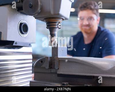 Engineer operating drill through CNC machine at factory Stock Photo