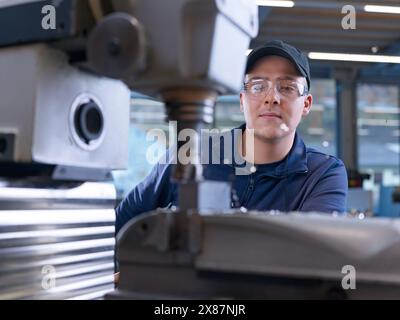 Engineer wearing cap working with CNC machine at factory Stock Photo